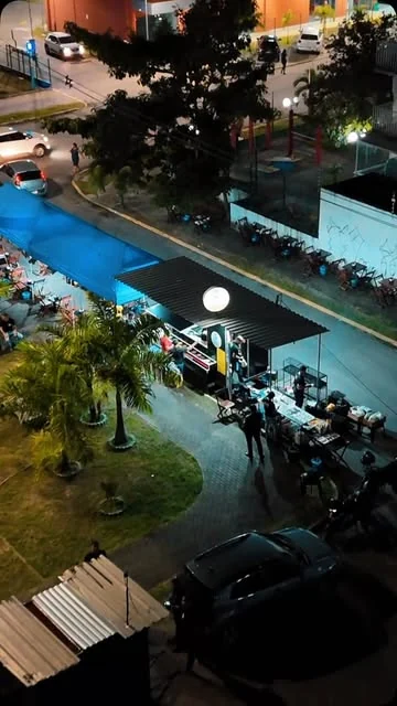 Vista de cima do quiosque e das mesas do Seu João na praça, à noite